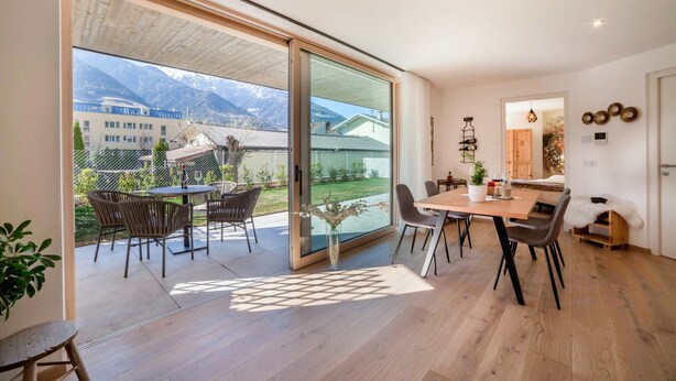 A modern interior with a dining area, large sliding glass doors, and a view of mountains.