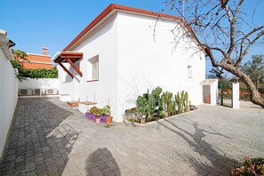 Un bâtiment blanc avec un toit rouge, une cour pavée et des plantes en pot.