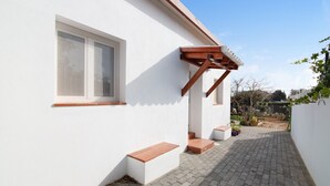 Een wit gebouw met een raam, houten trappen en een geplaveid pad.