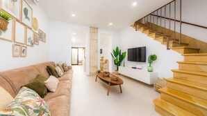 A modern living room with a sofa, coffee table, and a staircase. - Holiday Home "Ca Na Lola" Near the Beach with Wi-Fi, Air Conditioning & Terrace (Portocristo)