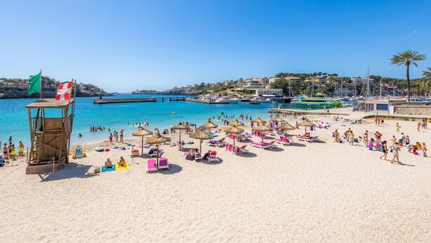 A beach with a lifeguard tower, umbrellas, and beach chairs. - Holiday Home "Ca Na Lola" Near the Beach with Wi-Fi, Air Conditioning & Terrace (Portocristo)