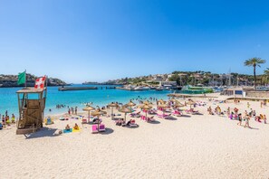 A beach with a lifeguard tower, umbrellas, and beach chairs. - Holiday Home "Ca Na Lola" Near the Beach with Wi-Fi, Air Conditioning & Terrace (Portocristo)
