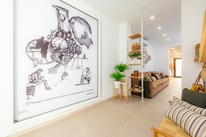 Un salon avec une grande œuvre d’art murale, un canapé, une table basse et une plante en pot.