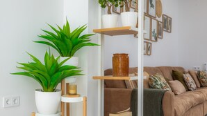 A living room with a brown sofa, a white coffee table, a bookshelf, and two potted plants. - Holiday Home "Ca Na Lola" Near the Beach with Wi-Fi, Air Conditioning & Terrace (Portocristo)