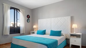 A bedroom with a large bed, two bedside tables, a window with curtains, and a wall with a clock and a star decoration. - Apartment "La Estrella" Near Beach with Panoramic Sea View, Terrace, A/C & Wi-Fi (Playa Blanca)
