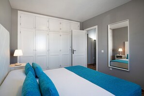 Une chambre à coucher comprenant un lit, une table de chevet, un miroir et une armoire.