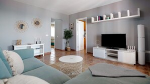A living room with a sofa, a coffee table, a TV, and a white entertainment unit. - Apartment "La Estrella" Near Beach with Panoramic Sea View, Terrace, A/C & Wi-Fi (Playa Blanca)
