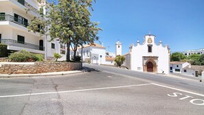 Une rue bordée d’un bâtiment blanc, doté d’un clocher et d’un mur en pierre.