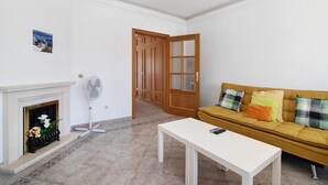 Un salon avec une cheminée, un canapé, une table et une porte donnant sur une autre pièce.