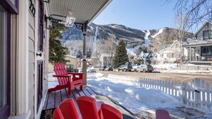 A porch with red Adirondack chairs, a welcome mat, and a view of a snowy mountain and town. - Sunnyside Retreat Home (Telluride)