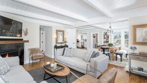A spacious living room with a fireplace, a sofa, a coffee table, and a dining area with a chandelier. - Sunnyside Retreat Home (Telluride)