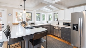 A modern kitchen with a central island, stainless steel appliances, and large windows. - Sunnyside Retreat Home (Telluride)