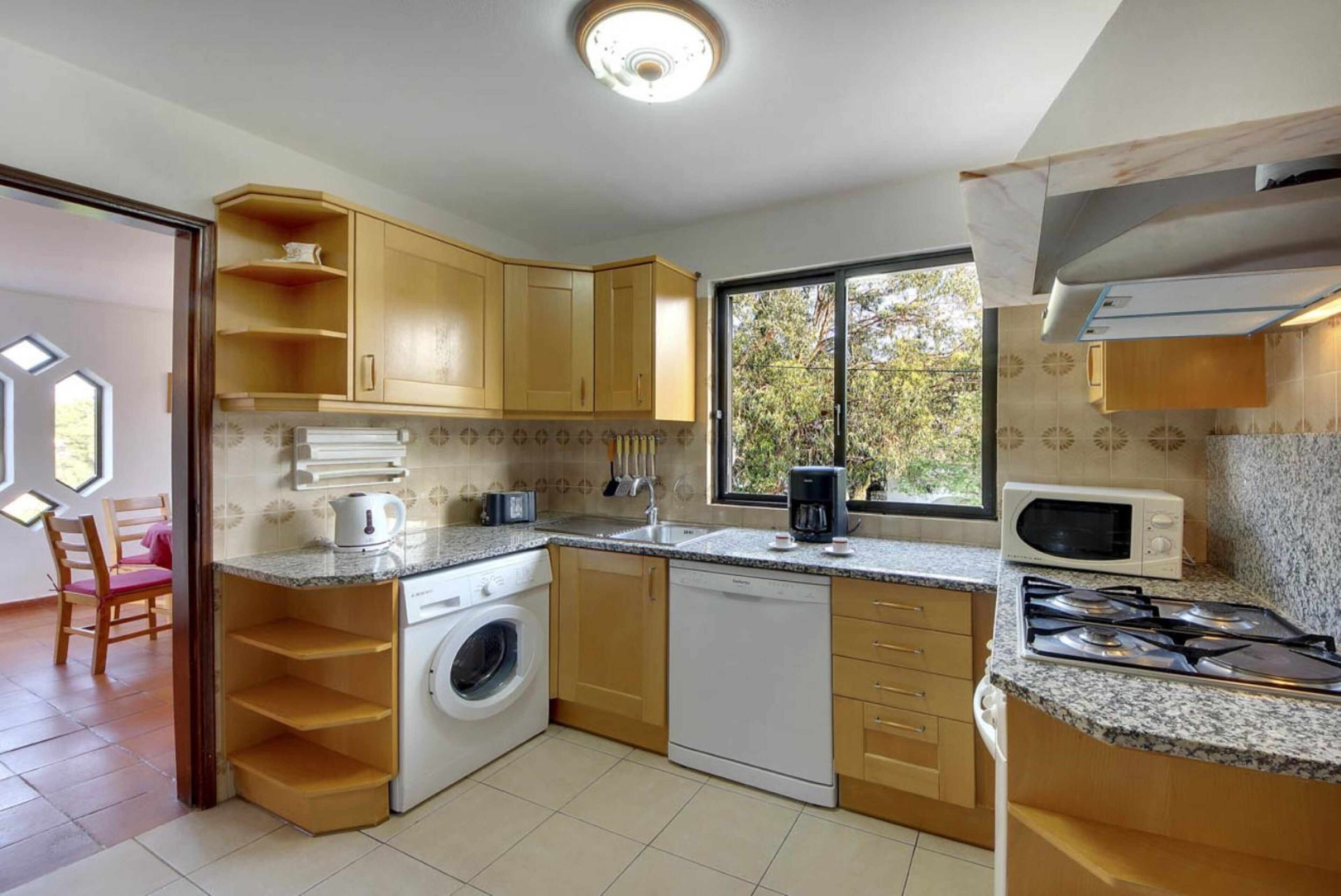 A compact kitchen with a washing machine, dishwasher, microwave, and stove.