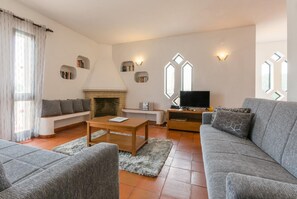 Una sala de estar con un sofá, una mesa de centro, una chimenea y un televisor.