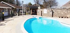 En swimmingpool med en mur av sten och en byggnad i bakgrunden.