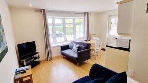 A living room with a TV, sofa, and dining area. - Foxes Lair  Holiday Home Looe Cornwall (Looe)