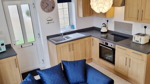 Una cocina compacta con armarios de madera, microondas, hervidor y tostadora.