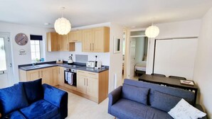 Un espacio habitable compacto con kitchenette, dos sofás y una mesa de comedor.