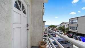 Un balcon donnant sur une rangée de voitures garées et sur un immeuble situé de l’autre côté de la rue.