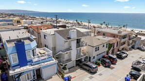Un quartier résidentiel situé sur la côte, avec des immeubles à plusieurs étages, une plage et des voitures garées.
