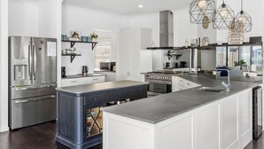A modern kitchen with stainless steel appliances, a central island, and pendant lighting.