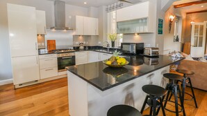 Una cocina moderna con armarios blancos, una isla central con taburetes, una estufa y un microondas.