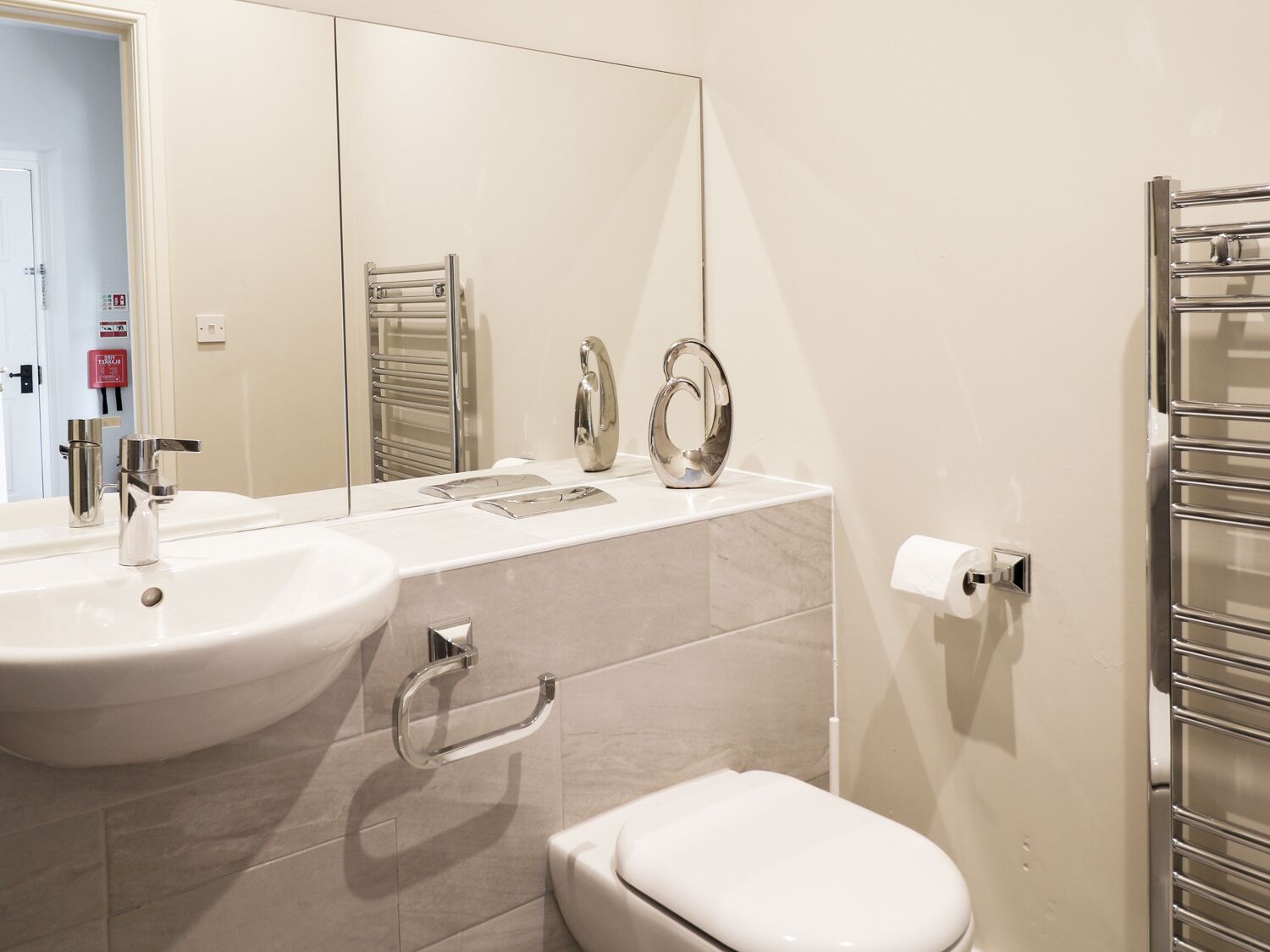 Un baño moderno con dos lavamanos, un inodoro y un perchero para toallas.