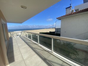 A balcony with a view of the beach and ocean.