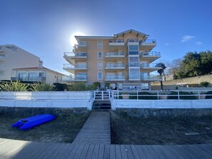 A multi-story residential building with balconies, a wooden pathway leading to the entrance, and a clear sky. - T3 in Arcachon with sea view, private parking, and Wi-Fi (Arcachon)