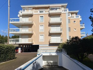 A multi-story residential building with balconies, a garage entrance, and a clear sky.