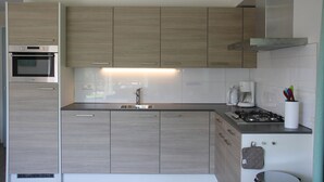Una cucina moderna con mobili in legno, forno integrato, piano cottura a gas e macchina da caffè.