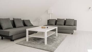 Een moderne woonkamer met twee grijze banken, een witte salontafel en een grijs vloerkleed.