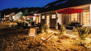 Una hilera de casas con espacios de estar al aire libre, cada uno con un paraguas rojo y macetas con plantas.