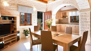 A modern kitchen with stone walls, wooden cabinetry, and a dining area with a wooden table and chairs.