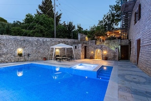 Piscina com parede de pedra e área de estar coberta.