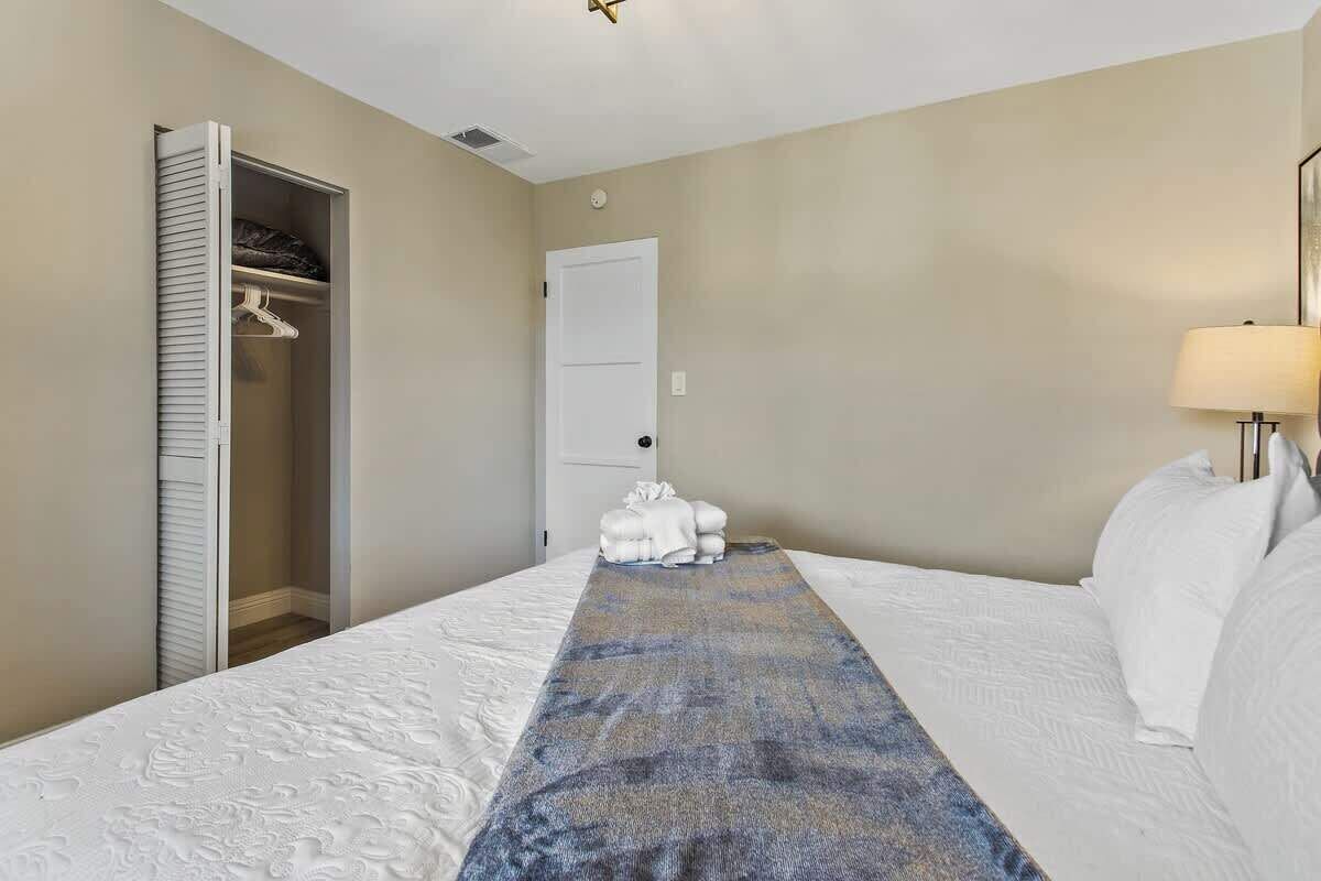 Una habitación de hotel con cama, vestidor, puerta y lámpara.