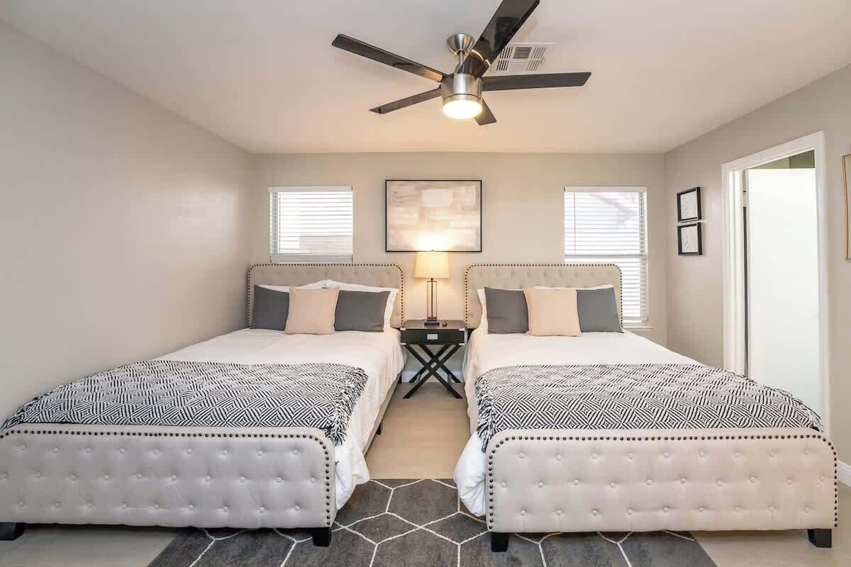 A bedroom with two beds, a ceiling fan, a nightstand, and a framed picture on the wall.