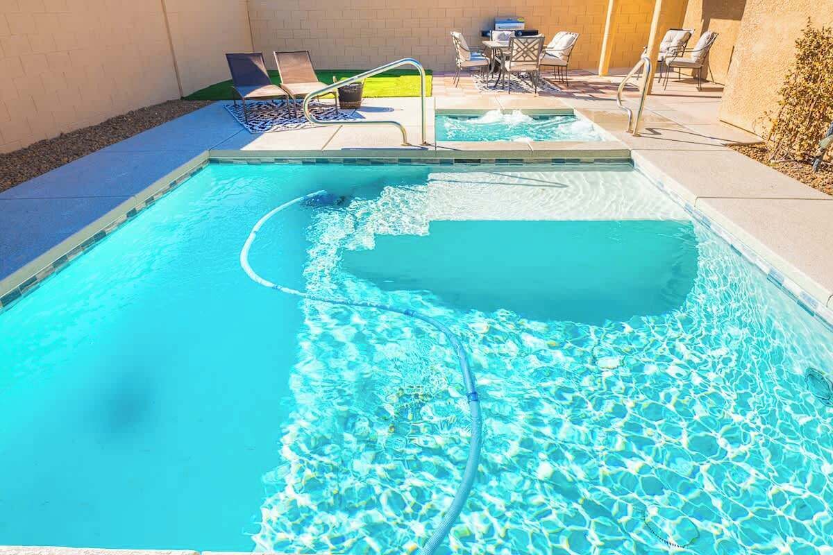 A swimming pool with clear water, a diving board, and lounge chairs.