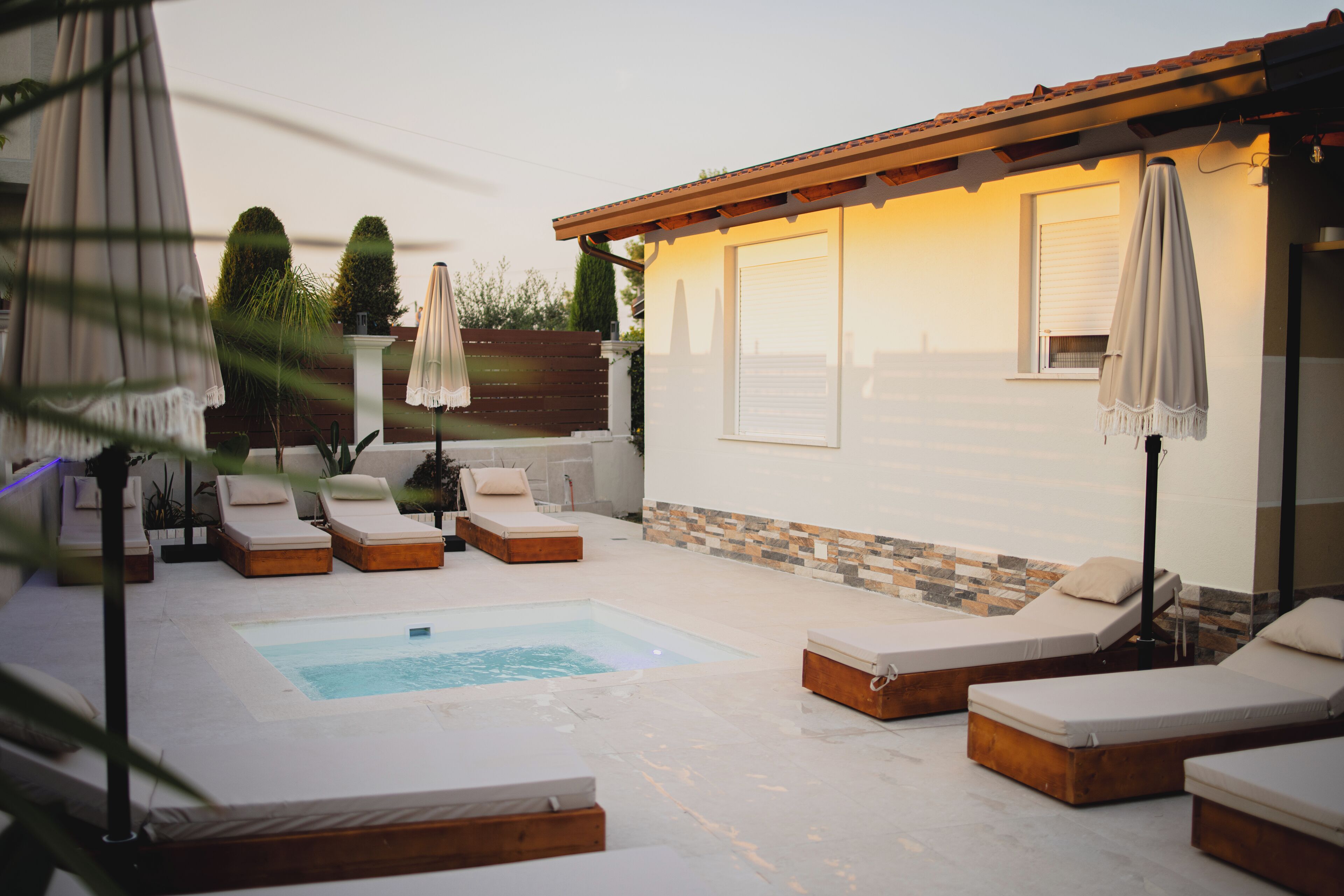 A poolside area with sun loungers, a hot tub, and a covered seating area.