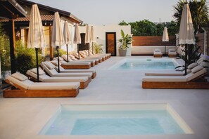 A pool area with sun loungers and umbrellas, surrounded by a wooden deck and potted plants. - Lej & Laj Residence (Sukth)