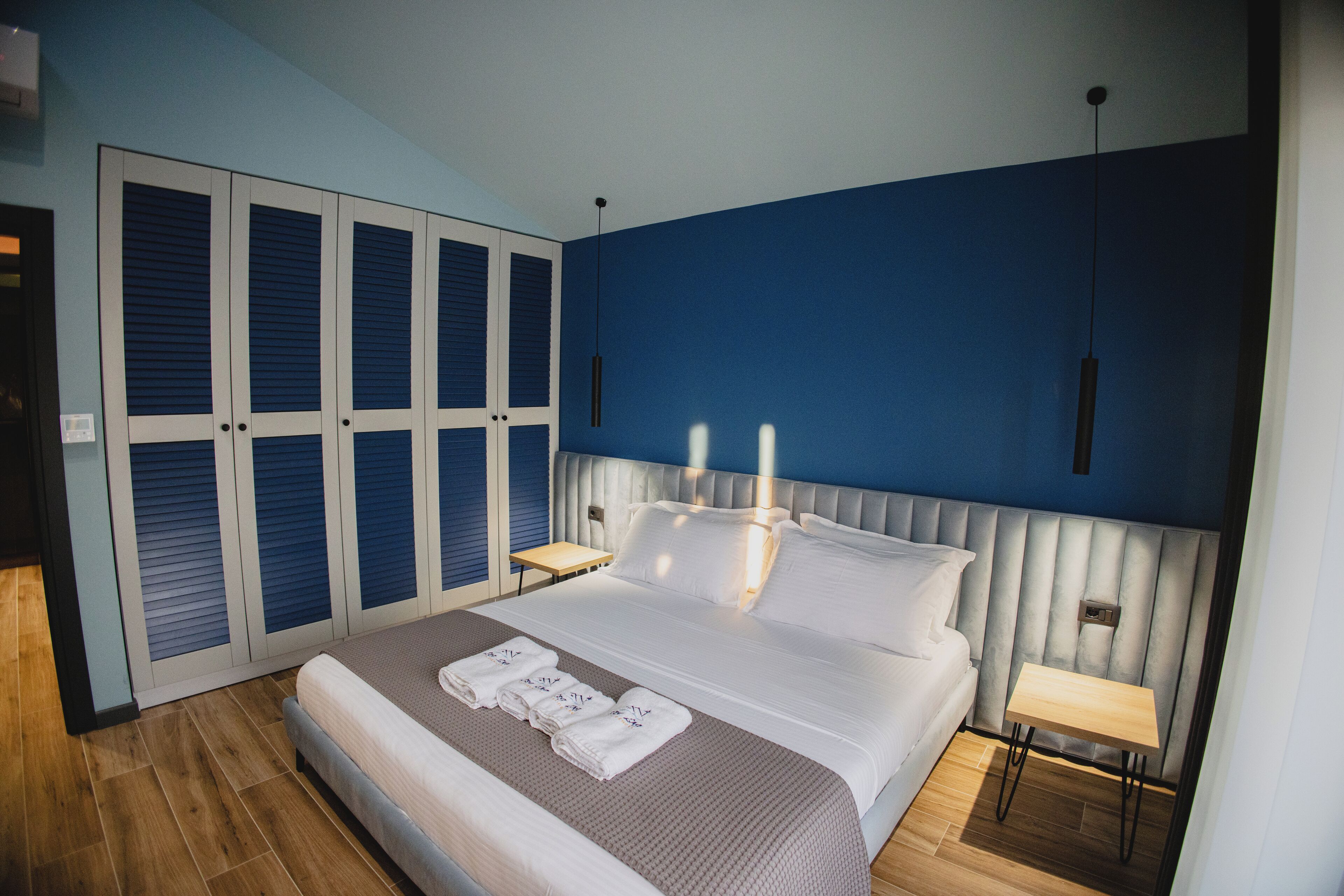 Una habitación de hotel con una cama grande, un armario con puertas correderas, una mesita de noche y una lámpara de noche.