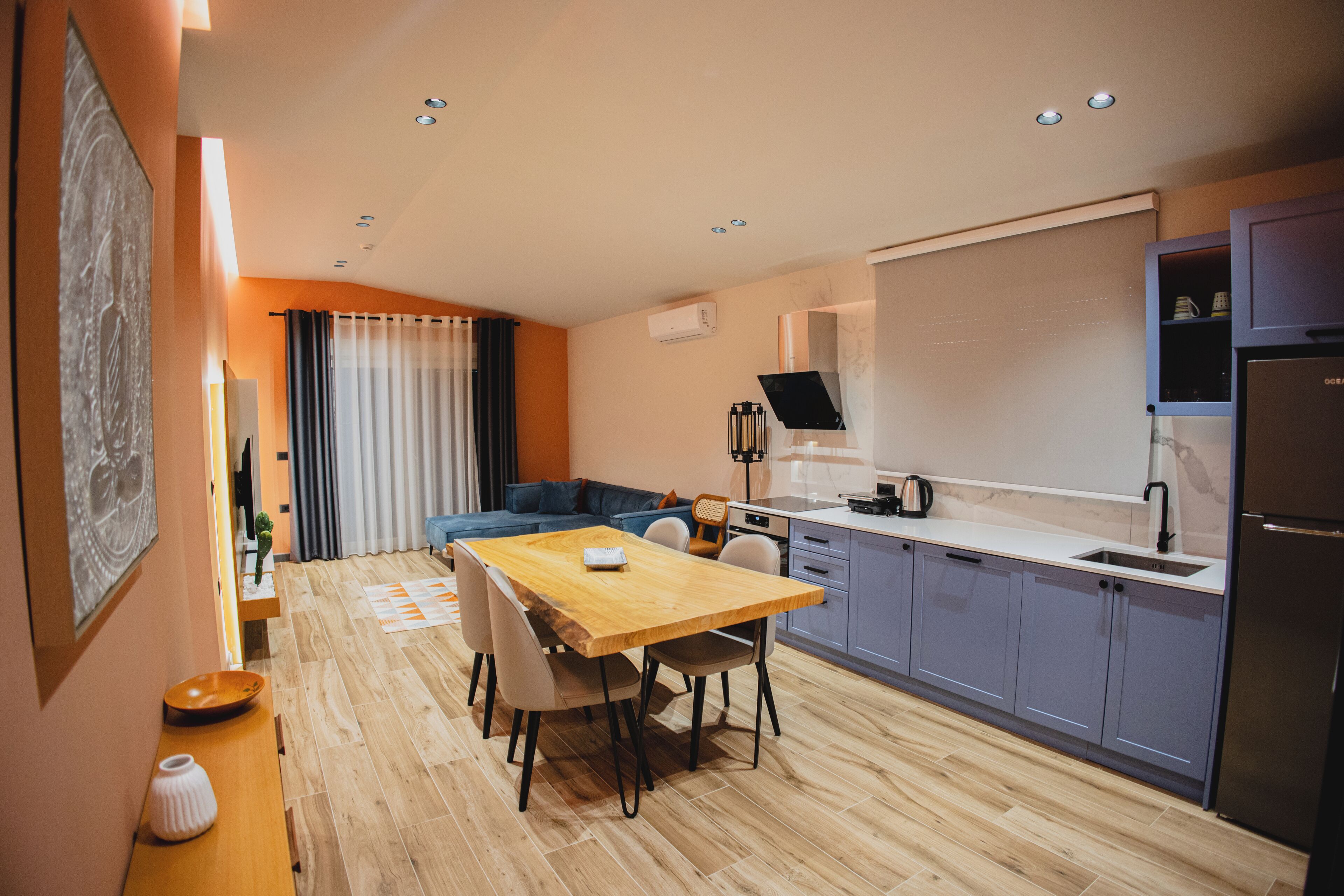 A modern kitchen with grey cabinets, a wooden dining table, and a built-in oven.