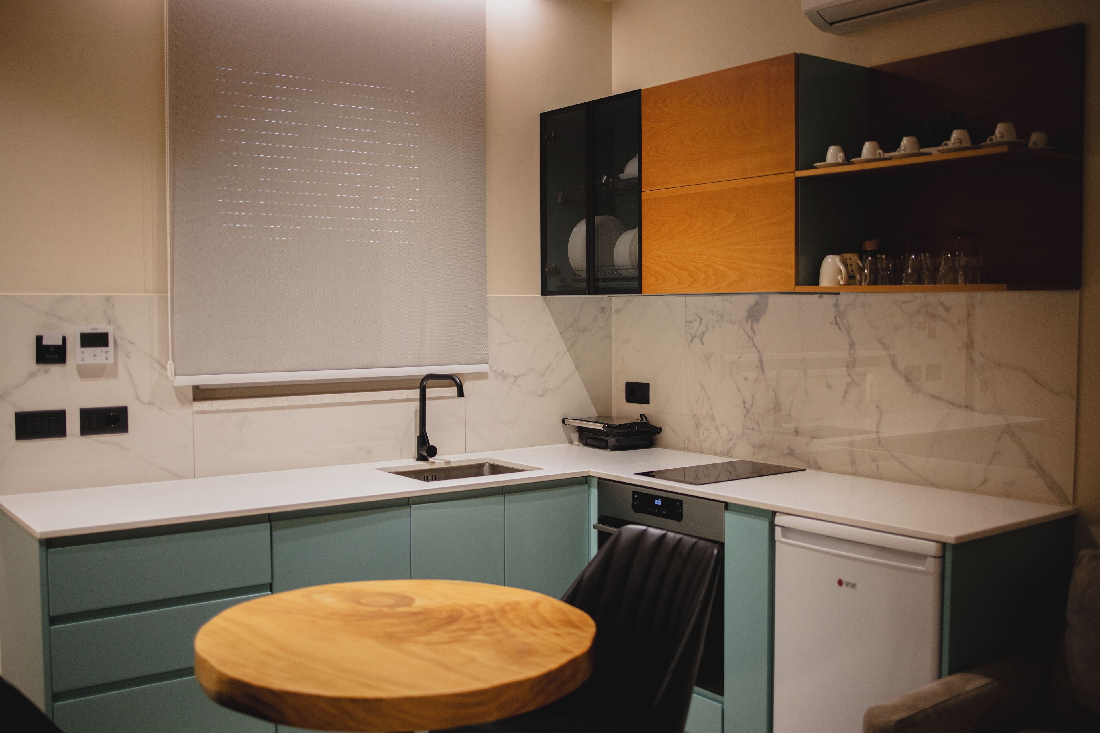 A modern kitchen with a sink, stove, and a dining area with a wooden table and chairs.