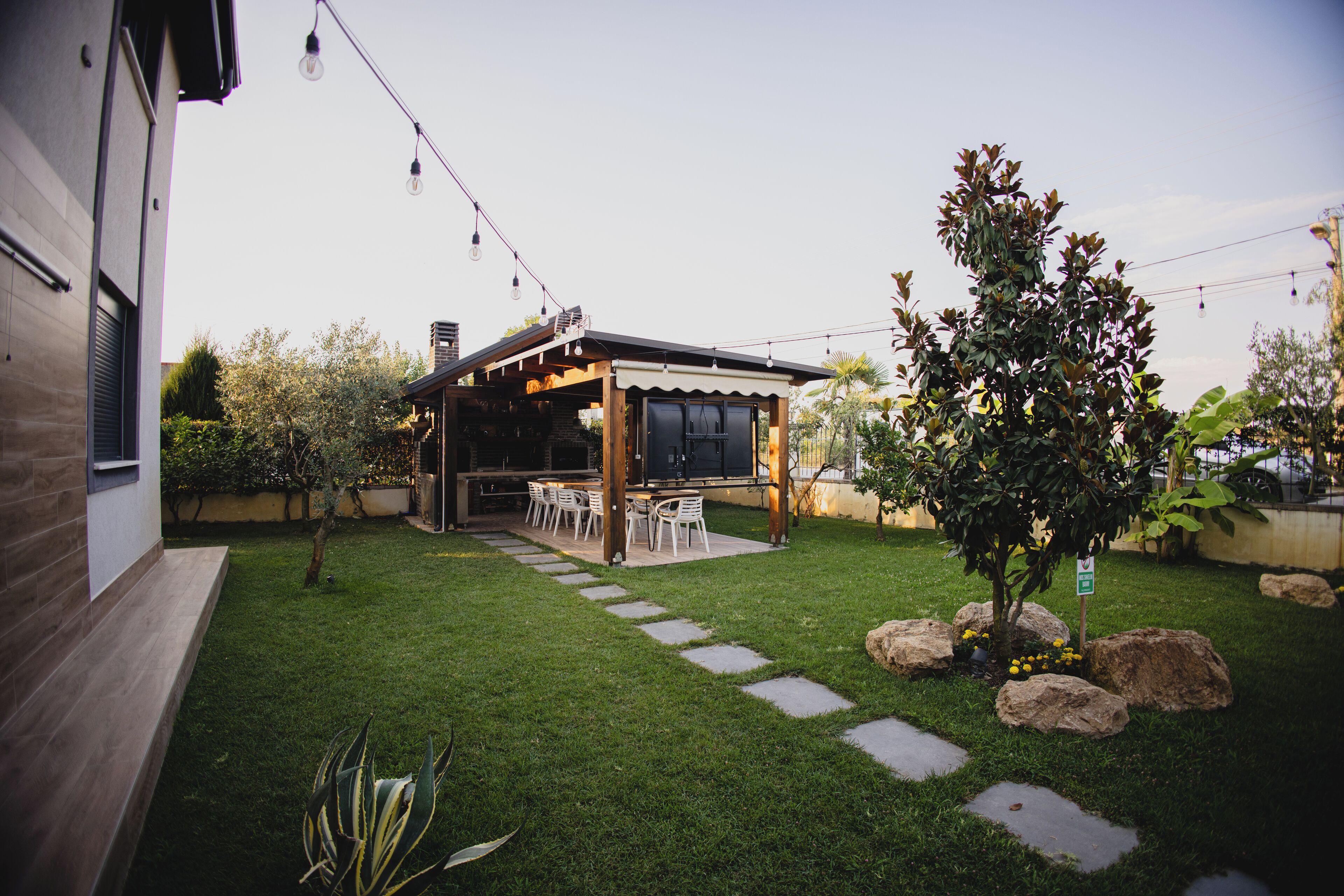 A backyard with a patio, outdoor seating, and a small tree.