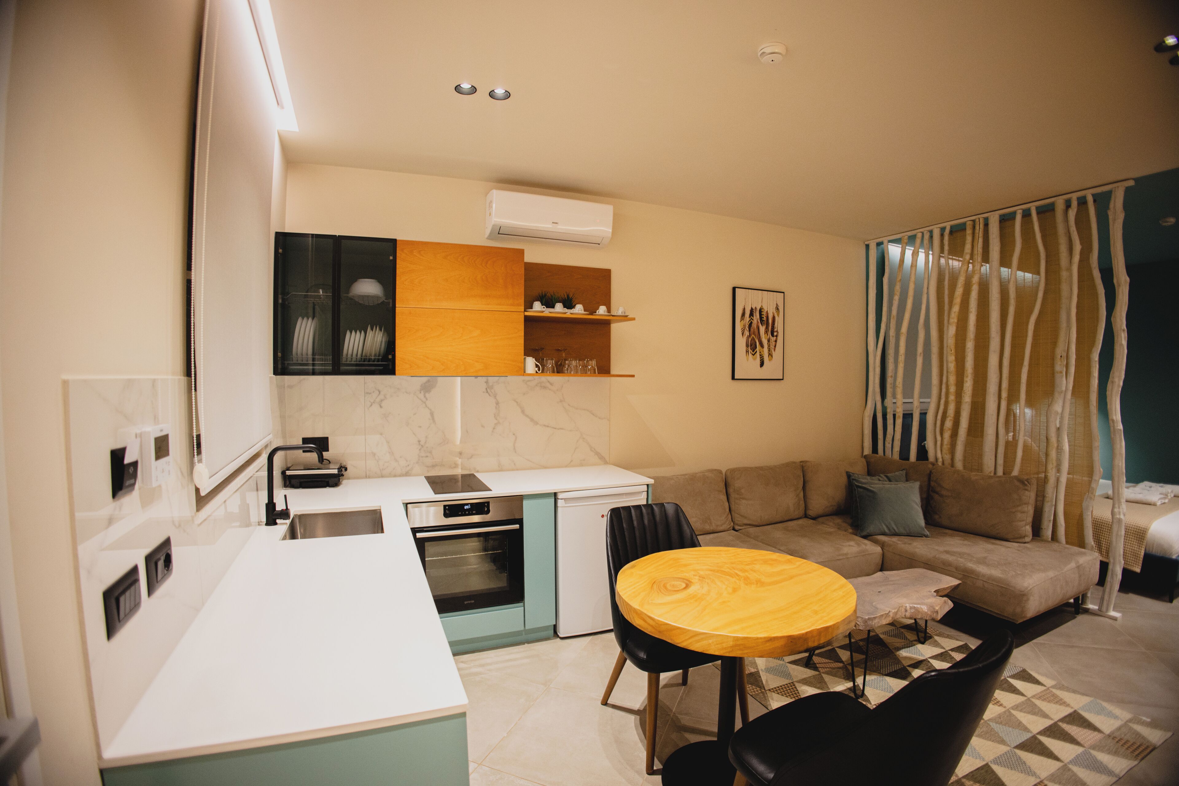 Ett kompakt bostadsutrymme med ett litet kök, en matplats och en soffa.