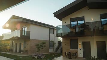A modern two-story house with a balcony, a staircase, and a small garden area.