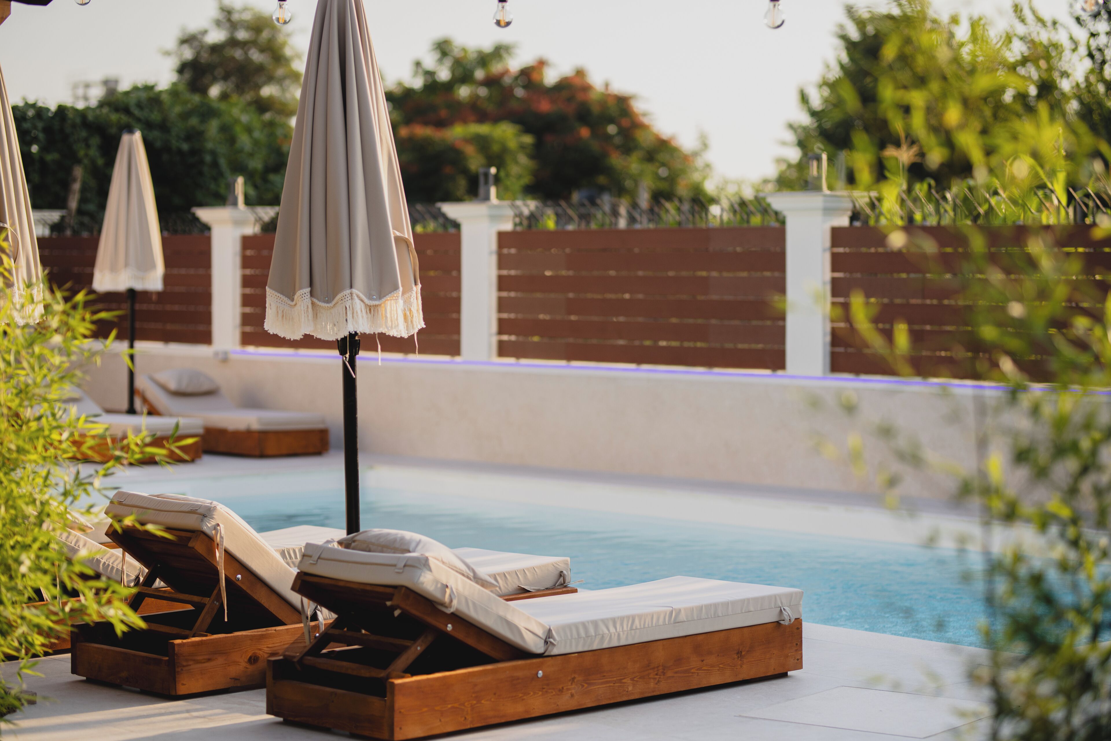 A poolside area with wooden loungers and umbrellas.
