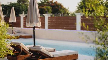 A poolside area with wooden loungers and umbrellas.