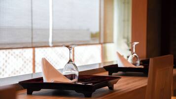Un comedor con una mesa y sillas de madera, una ventana con persianas, y un florero sobre la mesa.