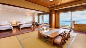 A hotel room with two beds, a dining table, chairs, a sofa, and large windows offering a view of the sea. - amafuru-oka (Ibusuki)